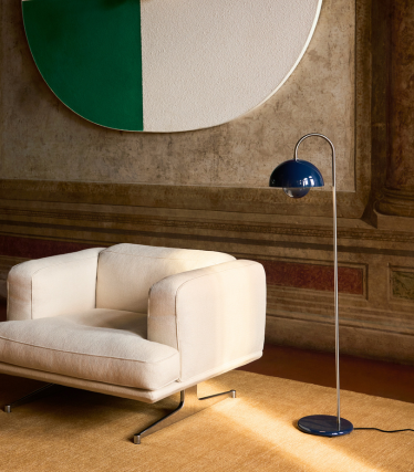 Elegantna podna svjetiljka &Tradition uz modernu lounge fotelju u ugodnom interijeru.