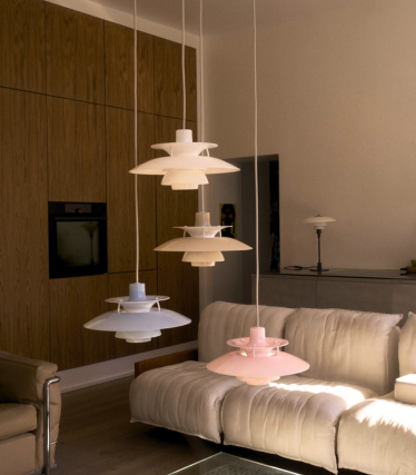 Blaue kegelförmige Pendelleuchte über rundem blauem Esstisch mit Blumenstrauß, in einem Esszimmer mit blauer Wand und Kunstwerken.