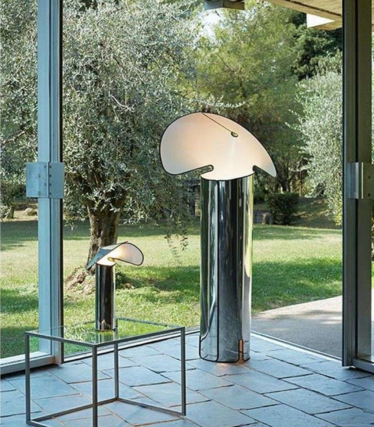 Dvije sjajne podne lampe sa zakrivljenim sjenilima u obliku lista ispred prozora s pogledom na vrt.
